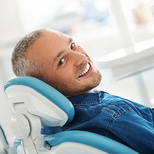 Book a professional oral hygiene cleaning with our hygienists today! A man smiling while in a dental chair.
