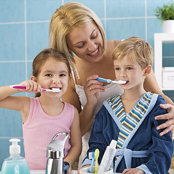 A mom teaching her kids how to brush their teeth